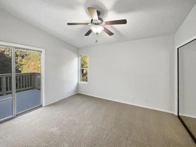an empty room with windows and fan
