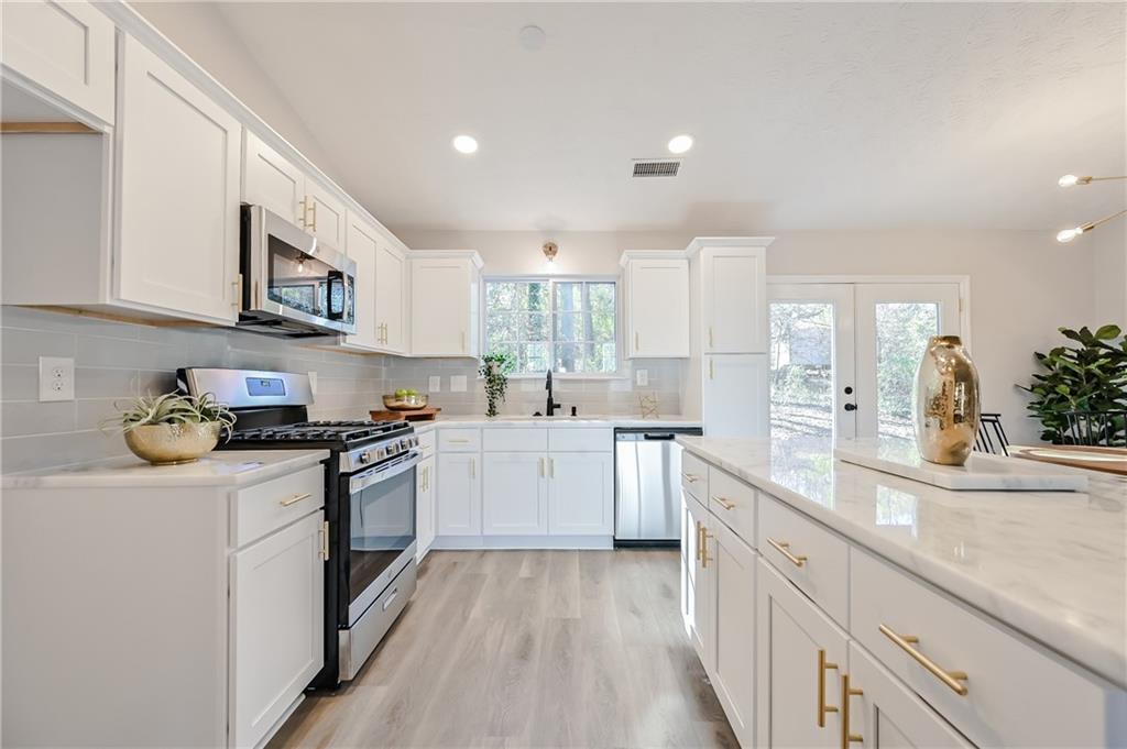 a kitchen with stainless steel appliances granite countertop a stove a sink dishwasher and a refrigerator with wooden cabinets