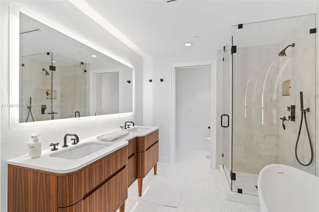 a bathroom with a tub sink double mirror and shower
