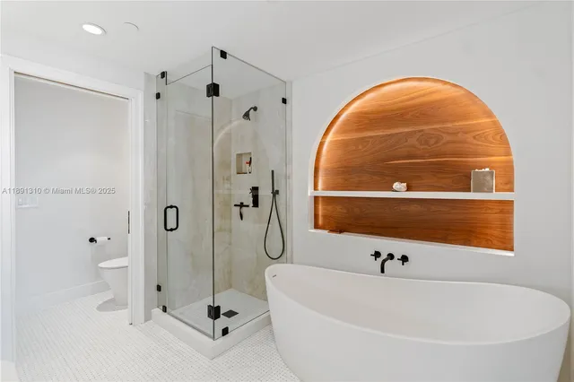 a bathroom with a tub a mirror and glass door