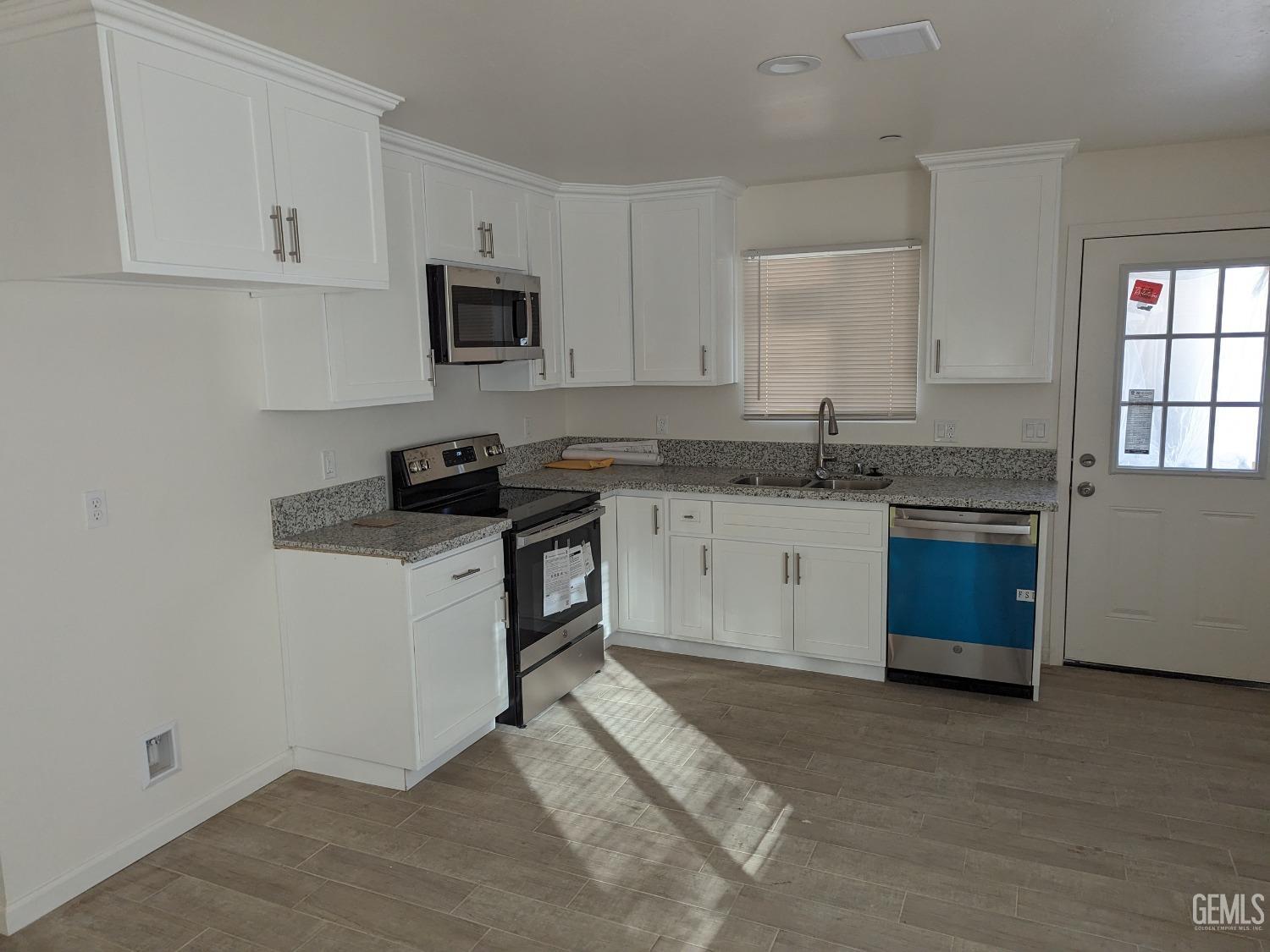 Undisclosed Address Bakersfield, CA 93308 - Photo 4 of 9 a kitchen with stainless steel appliances granite countertop a stove a sink dishwasher and a refrigerator with wooden cabinets