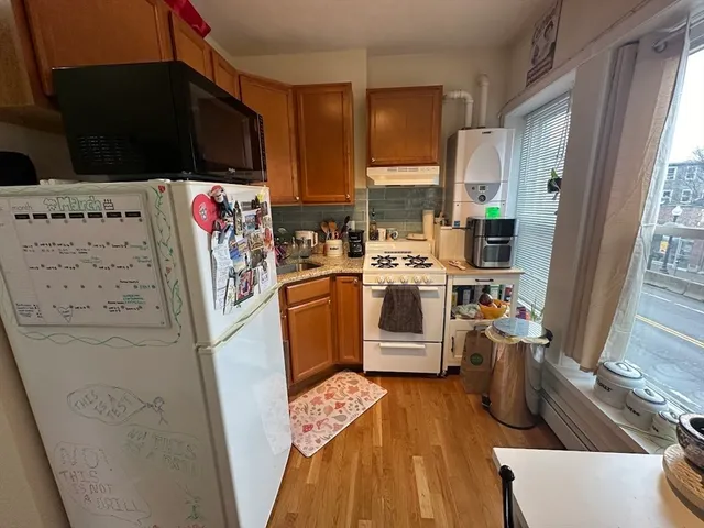 a view of a kitchen with fridge and wooden floor