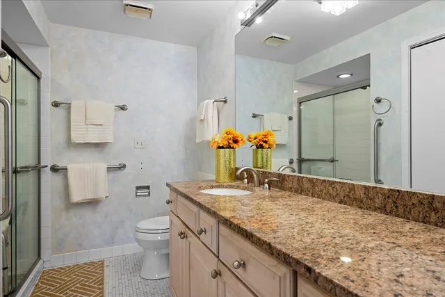 a bathroom with a granite countertop sink a toilet and shower