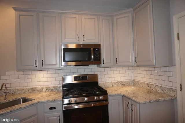 a kitchen with granite countertop white cabinets and a stove