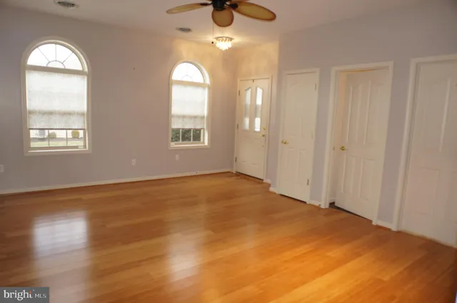 a view of empty room with wooden floor and fan