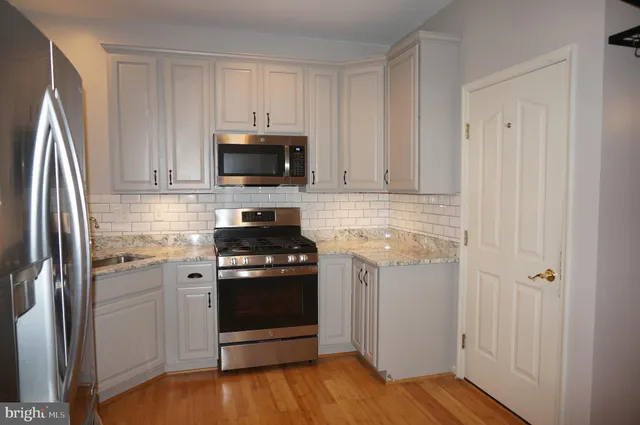 a kitchen with stainless steel appliances granite countertop a stove a refrigerator and a microwave