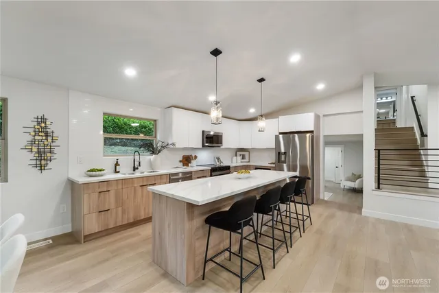 a open kitchen with stainless steel appliances granite countertop a sink a stove a refrigerator and island with wooden floor