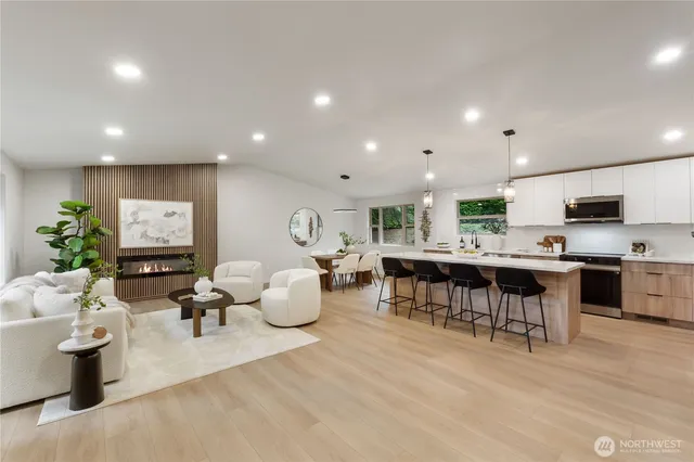 a living room with furniture a wooden floor and kitchen view