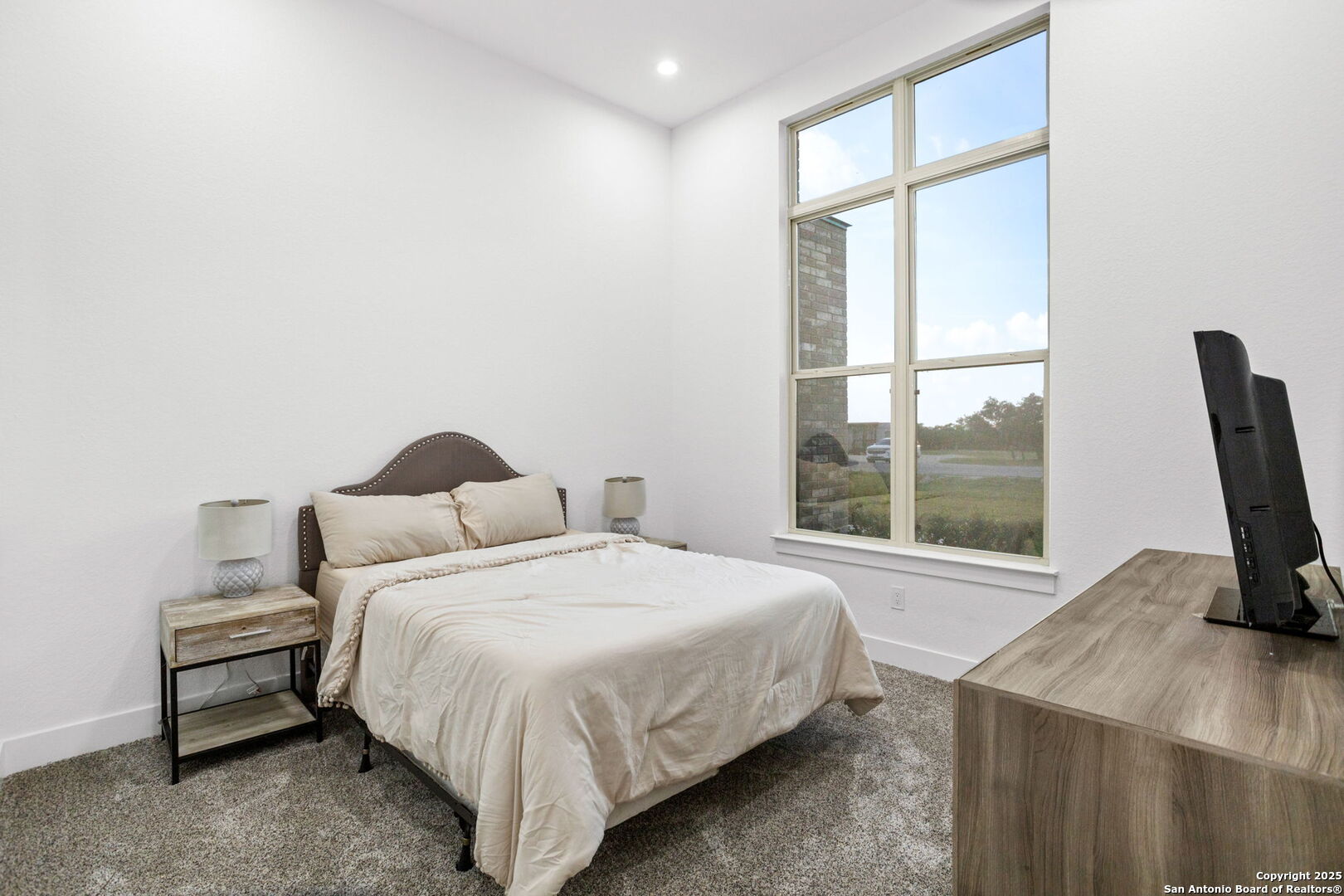 187 Stone Loop Castroville, TX 78009 - Photo 22 of 30 a bedroom with a bed a table and a large window