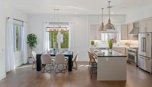 a dining room with stainless steel appliances granite countertop furniture wooden floor and a chandelier