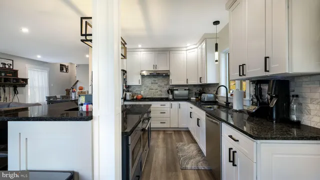 a kitchen with granite countertop a sink stove and cabinets