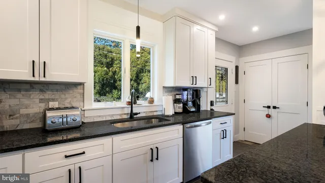a kitchen with stainless steel appliances granite countertop a sink a window and cabinets