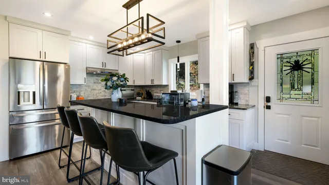 a kitchen with stainless steel appliances a table chairs refrigerator and microwave