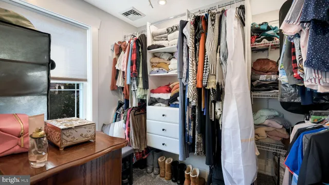 a view of walk in closet with clothes and shoes