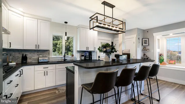 a kitchen with stainless steel appliances granite countertop a sink a stove a dining table and chairs