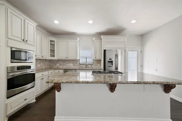 a kitchen with kitchen island granite countertop a stove sink and microwave