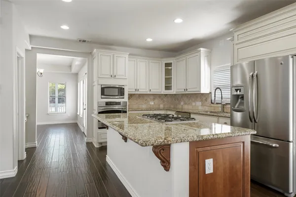 a kitchen with stainless steel appliances granite countertop a refrigerator a stove and a sink