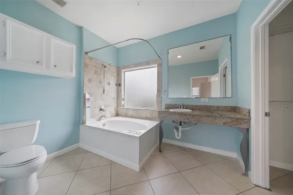 a spacious bathroom with a granite countertop sink a toilet and mirror
