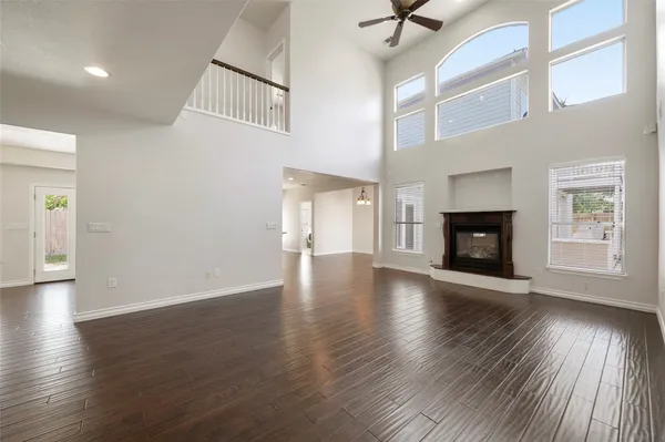 an empty room with wooden floor fireplace and windows
