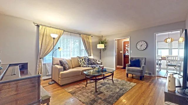 a living room with furniture a large window and wooden floor