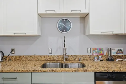 a kitchen with granite countertop a sink a stove and cabinets