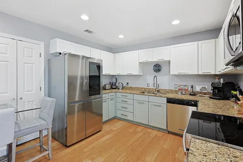 a kitchen with granite countertop a refrigerator stove top oven and sink