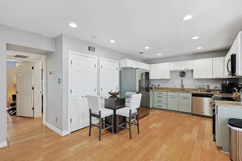 a kitchen with stainless steel appliances granite countertop a dining table chairs stove refrigerator and cabinets