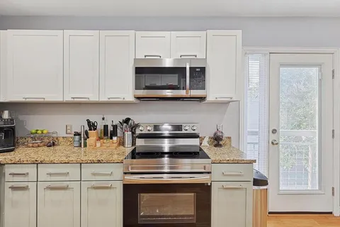 a kitchen with granite countertop white cabinets and a stove