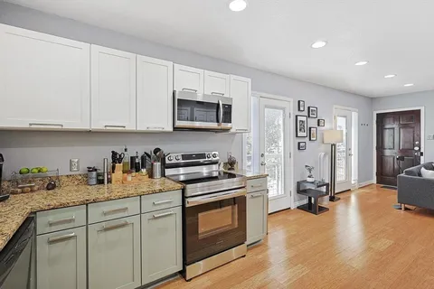 a kitchen with stainless steel appliances granite countertop a stove a sink dishwasher and a refrigerator with white cabinets