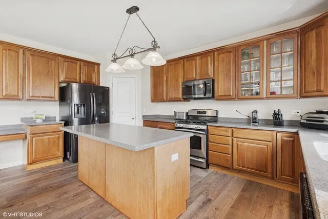 a kitchen with stainless steel appliances granite countertop a stove top oven a sink dishwasher and a refrigerator with wooden floor