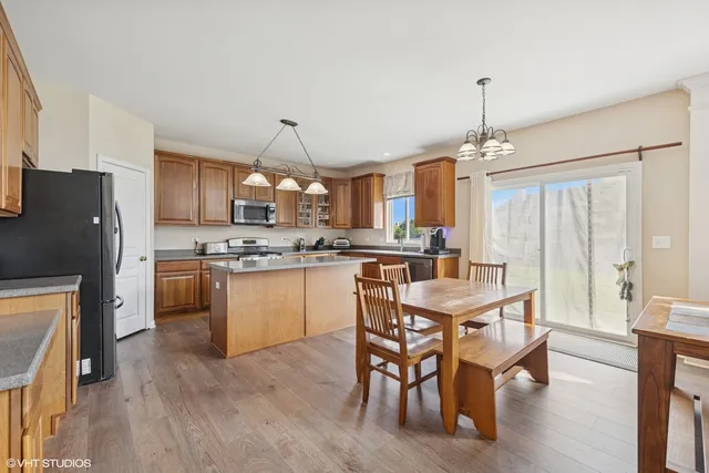 a kitchen with kitchen island granite countertop wooden floors and refrigerator