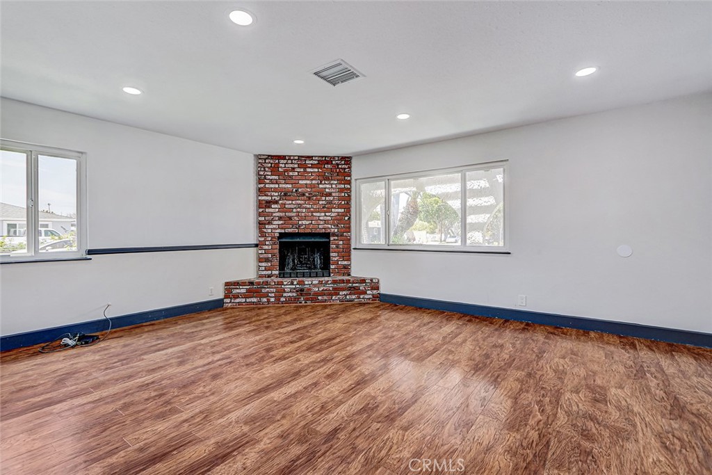15232 Purdy Street Westminster, CA 92683 - Photo 4 of 31 an empty room with wooden floor fireplace and windows