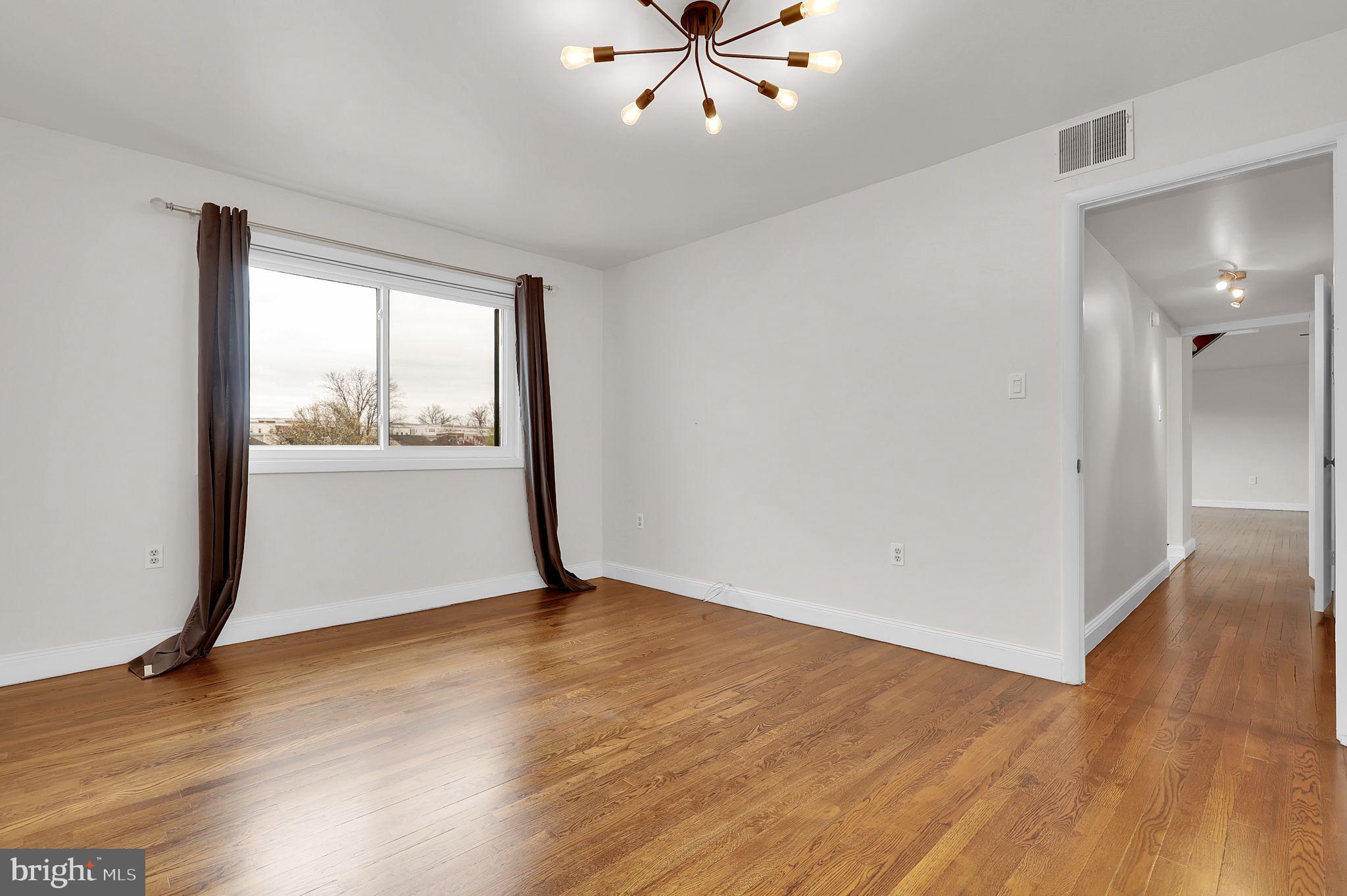 11514 Bucknell Drive, Unit 202 Silver Spring, MD 20902 - Photo 13 of 31 a view of an empty room with wooden floor and a window
