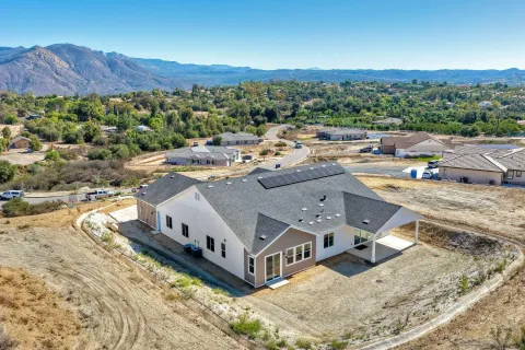 a front view of house with a yard and mountain view in back