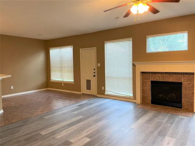 a view of an empty room with wooden floor fireplace and a window