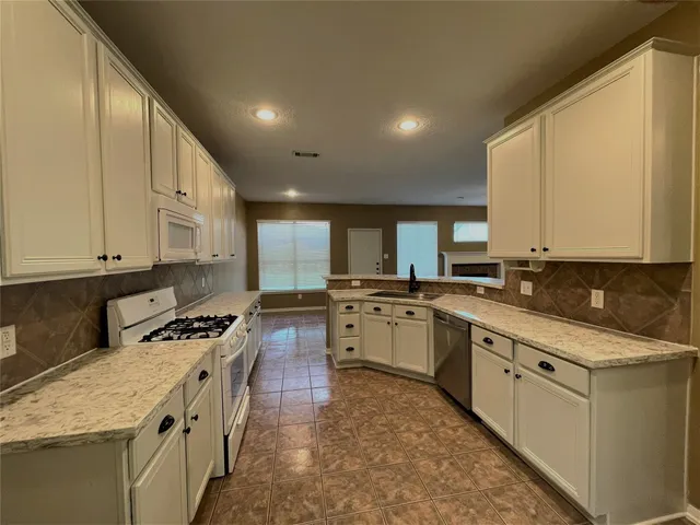 a kitchen with stainless steel appliances granite countertop a stove a sink and a microwave