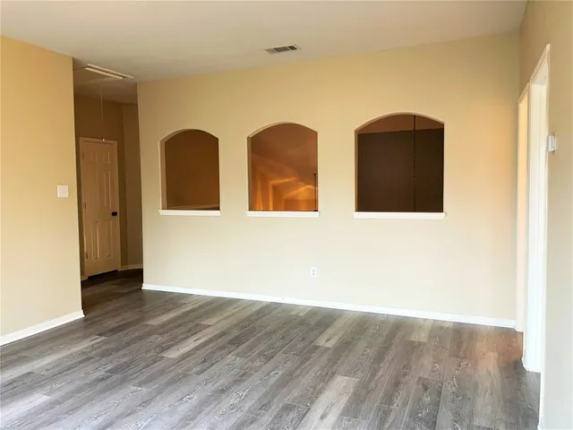 a view of an empty room with wooden floor and windows