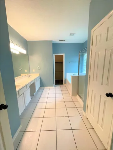 a spacious bathroom with a double vanity sink a toilet a mirror and shower