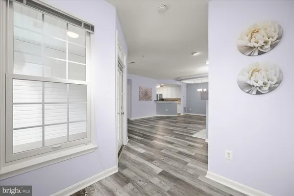 a view of a hallway to a bedroom with wooden floor and a window