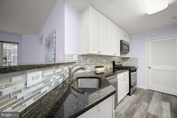 a kitchen with granite countertop a sink stove and refrigerator