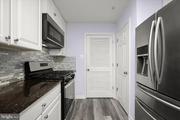 a kitchen with granite countertop a sink a stove and cabinets