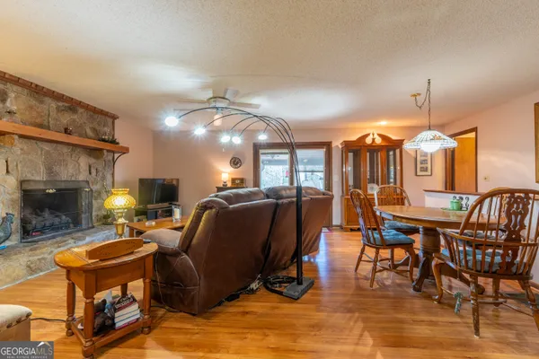 a living room with furniture a fireplace and a dining table with wooden floor