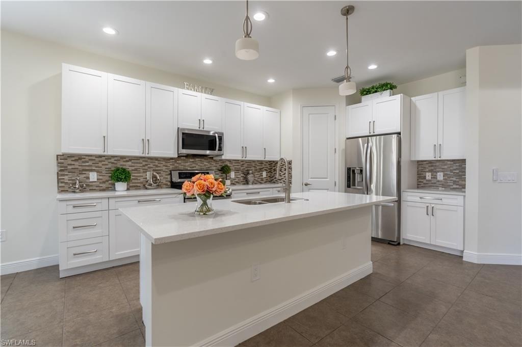 3549 Canopy Circle Naples, FL 34120 - Photo 12 of 50 a kitchen with white cabinets and stainless steel appliances