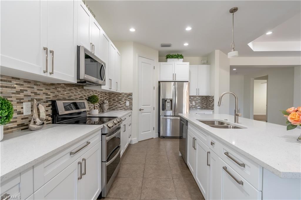 3549 Canopy Circle Naples, FL 34120 - Photo 14 of 50 a kitchen with stainless steel appliances granite countertop a sink stove refrigerator and cabinets