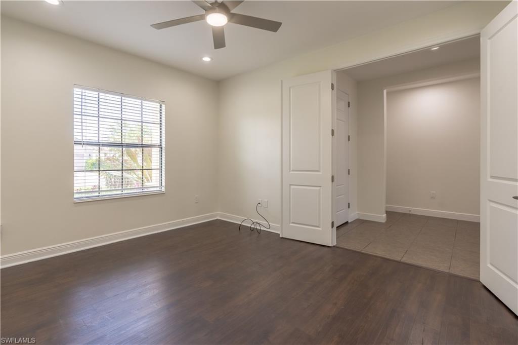 3549 Canopy Circle Naples, FL 34120 - Photo 19 of 50 an empty room with wooden floor chandelier fan and windows