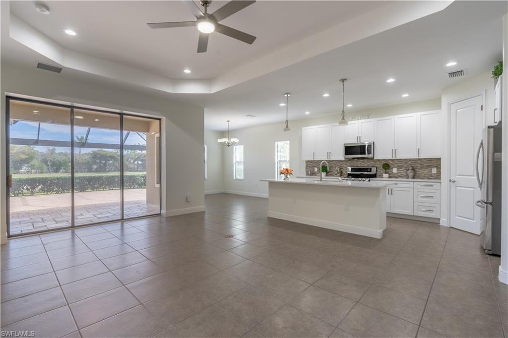 3549 Canopy Circle Naples, FL 34120 - Photo 8 of 50 a large kitchen with stainless steel appliances kitchen island granite countertop a stove a sink a refrigerator with white cabinets and couches