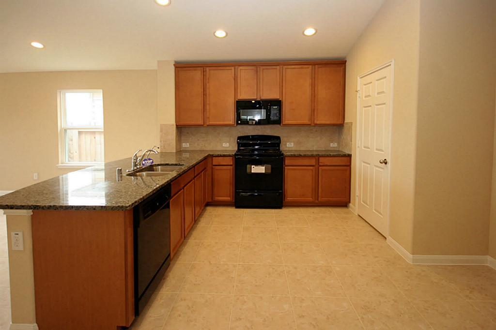 5427 Marble Ravine Richmond, TX 77407 - Photo 6 of 17 a kitchen with stainless steel appliances granite countertop a stove a sink and a refrigerator with wooden floor