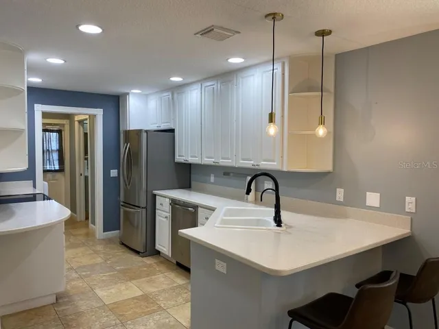 a kitchen with a sink a refrigerator and cabinets