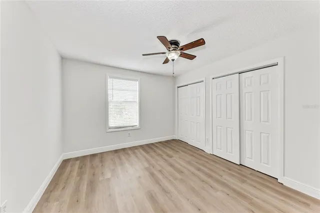 a view of empty room with wooden floor and fan