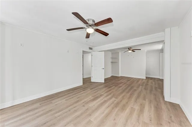 a view of empty room with wooden floor and ceiling fan